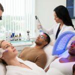 Diverse patients with different Fitzpatrick skin types receiving non-invasive skin rejuvenation treatments in a modern clinic — microneedling, fractional laser with cooling, RF device and LED therapy visible